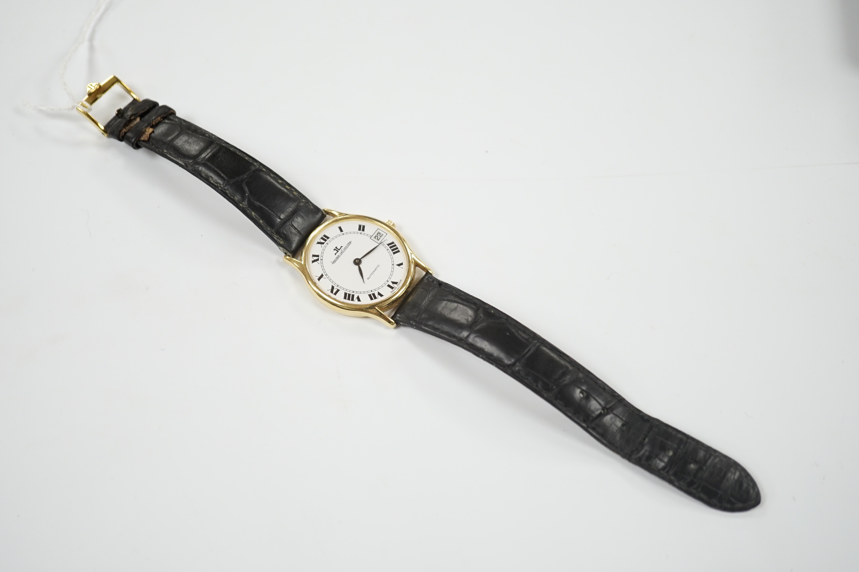 A gentleman's 18k Jaeger LeCoultre automatic dress wrist watch, with oval Roman dial and date aperture, on a leather strap with gold plated Jaeger buckle, case diameter 31mm, no box or papers.